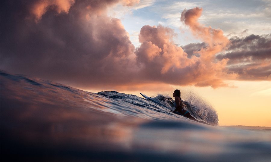 Woman riding a wave at sunset