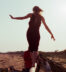 a woman walking on a log on a beautiful sand beach in a sunny day