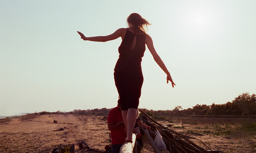 a woman walking on a log on a beautiful sand beach in a sunny day