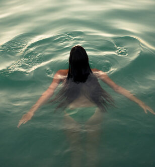 Woman with long hair swimming in the sea seen from aerial point of view