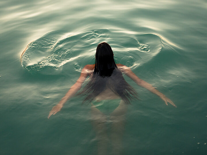 Woman with long hair swimming in the sea seen from aerial point of view