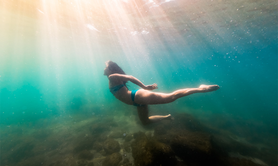 Woman in bikini diving exploring shallow blue green waters of Lake Ontario