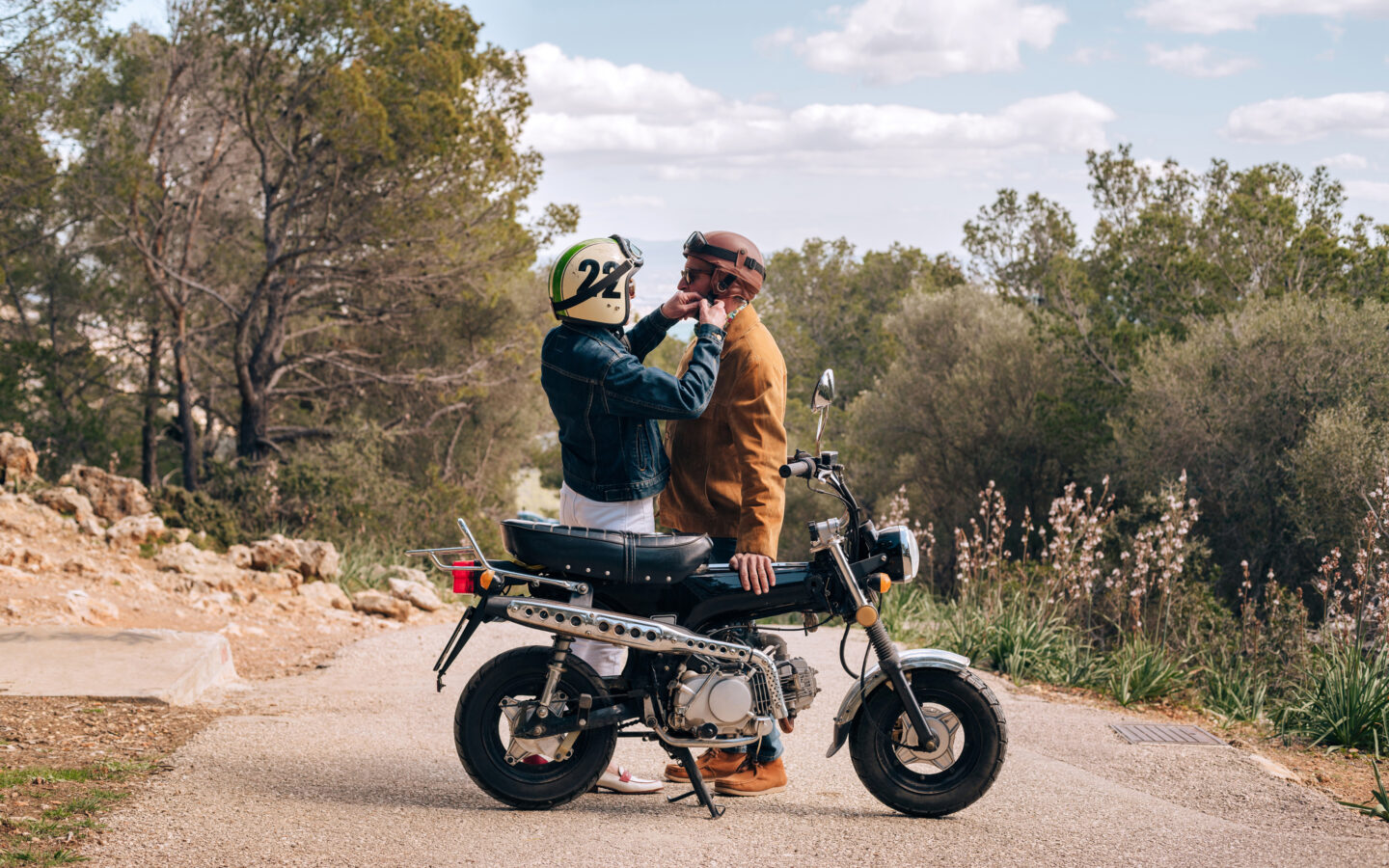 Couple adjusting their helmets, about to go on a ride with a vintage motorbike.