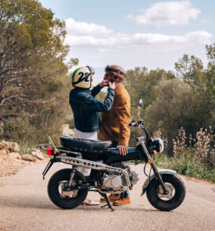 Couple adjusting their helmets, about to go on a ride with a vintage motorbike.
