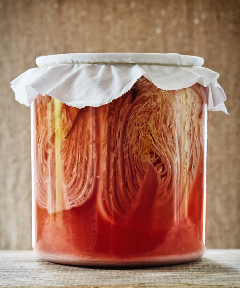 Fermented cabbage/ sauerkraut in glass jar on wood surface