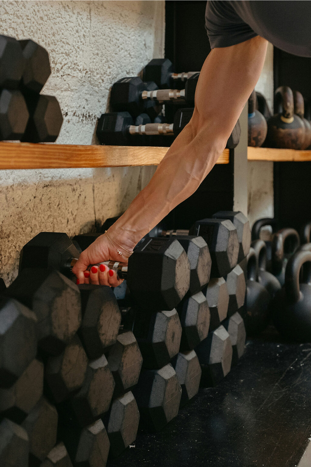 Hand selecting a dumbbell from a gym rack