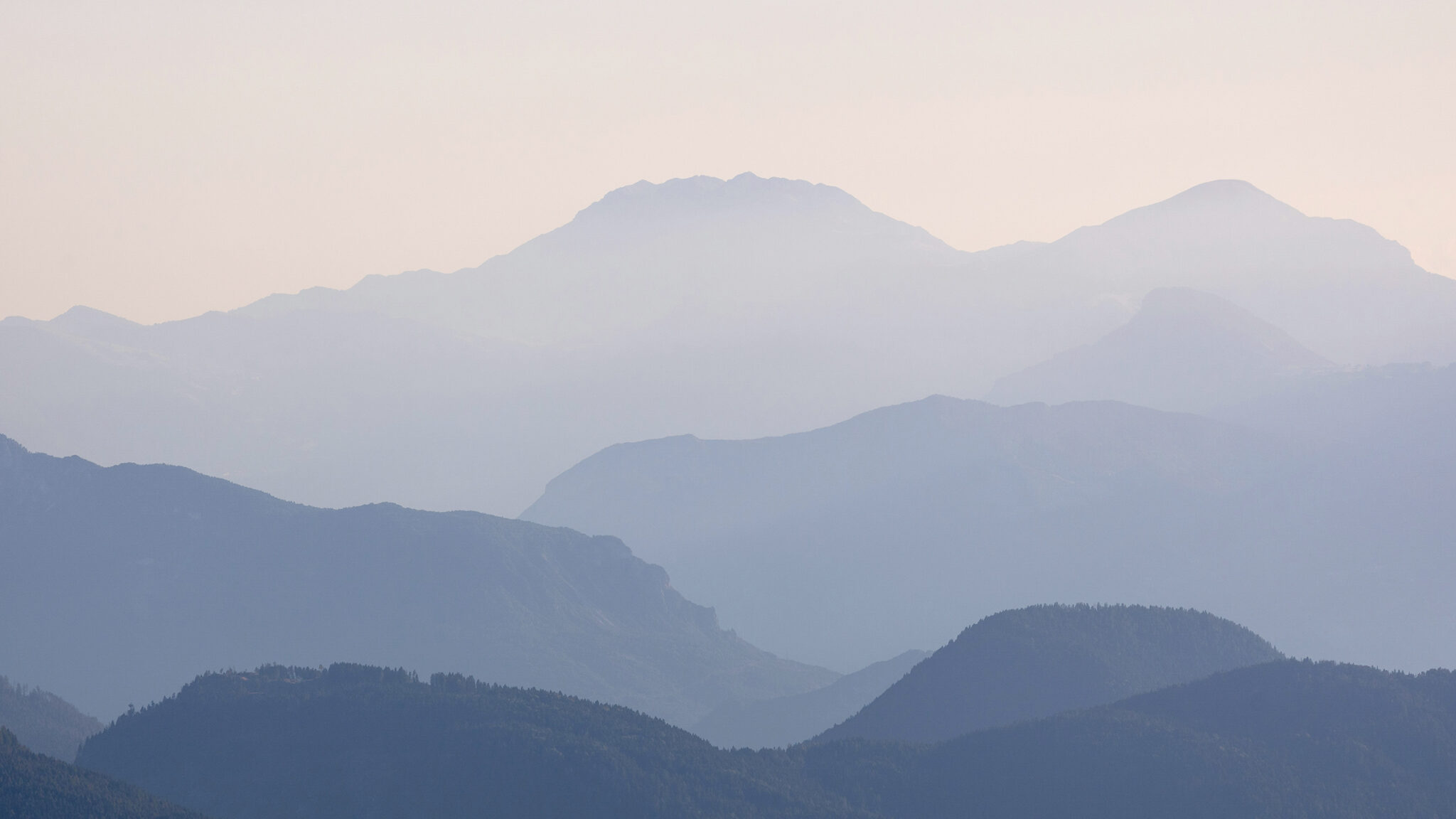 Layered misty mountain ridges in soft blue light